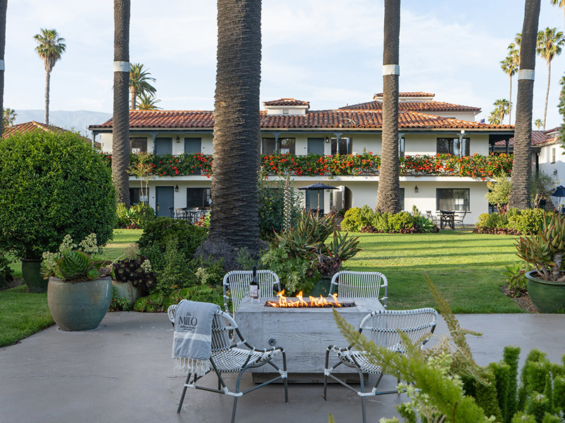a patio with a fire pit and chairs in front of a building