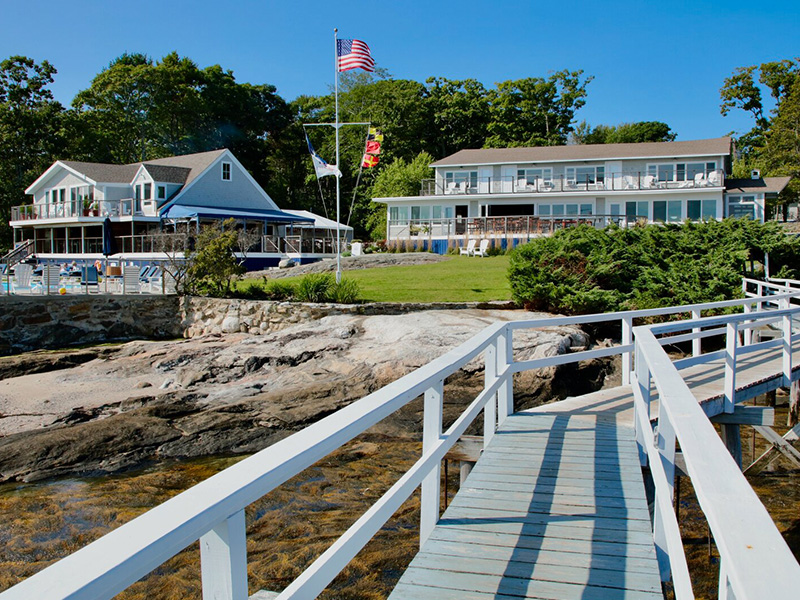 a bridge over water with a flag and buildings in the background