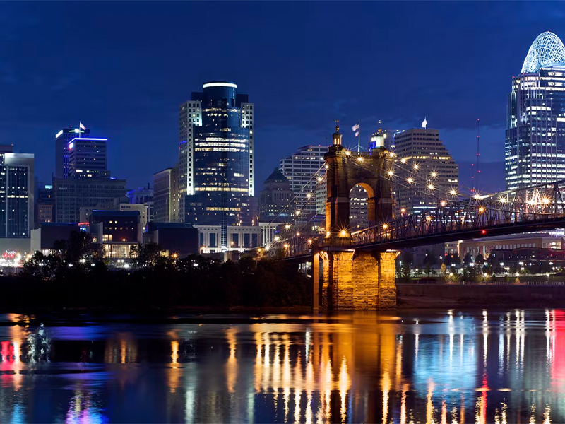 Nighttime skyline view of a city with a large bridge in the foreground